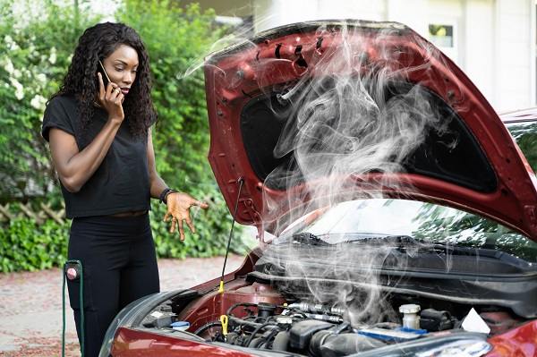 A car with an open hood. A man going over a check list.